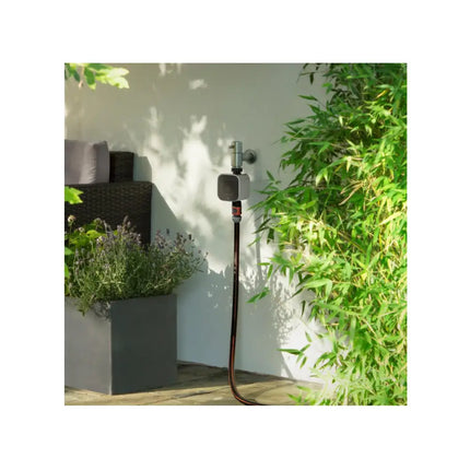 Weather-resistant Eve Aqua smart water valve controller installed on a garden faucet to prevent overwatering.
