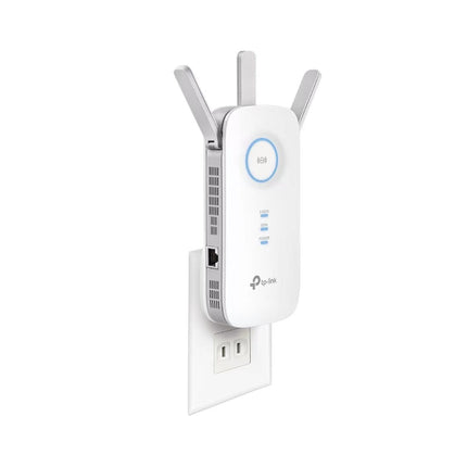 TP-Link RE450 Wi-Fi range booster plugged directly into a home hallway wall outlet, showing the intelligent signal indicator ring illuminated in blue.