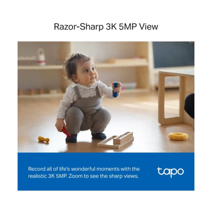 A TP-Link Tapo TC74 5MP security camera mounted on a living room shelf, showcasing its 360-degree horizontal pan coverage for home monitoring.