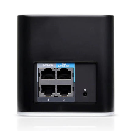 A sleek, black Ubiquiti airCube AC home access point blending subtly into a modern living room entertainment center setup.