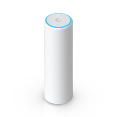Compact cylindrical white Ubiquiti UniFi U6 Mesh WiFi 6 access point standing upright on a desk with glowing blue LED status ring at the base.